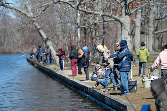 People standing on edge of lake and casting their fishing lines into the water