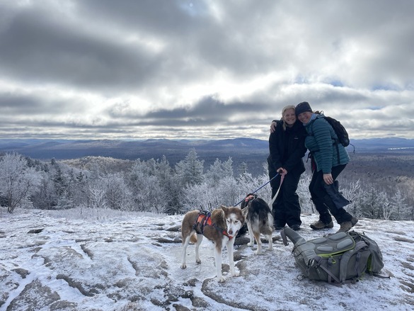 Two hikers and dogs on Coney Mountain snow-covered summit