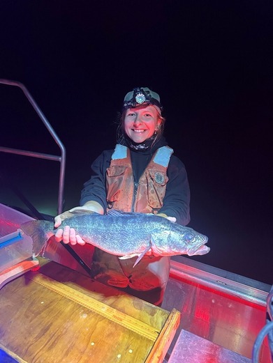 Person holding a walleye at night time