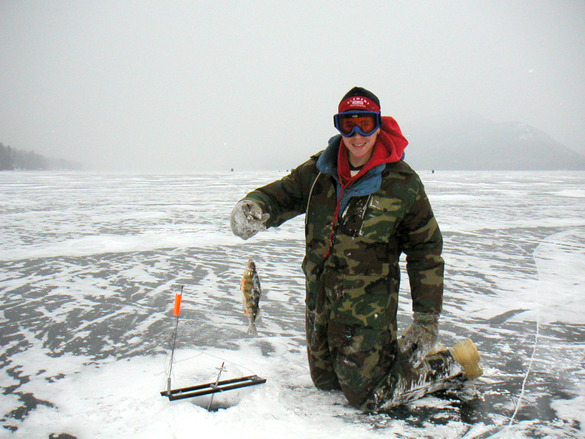 A person kneeling on ice holding a fish