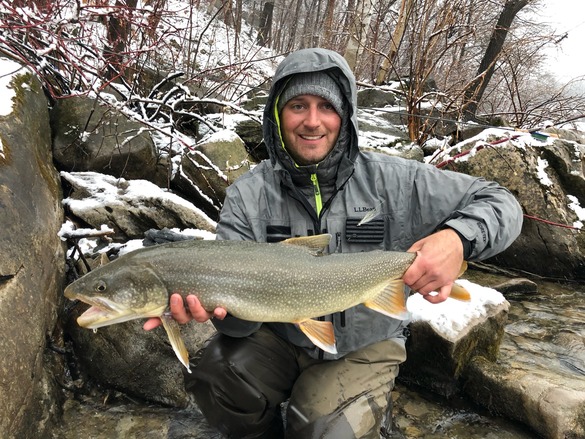 Angler in a winter setting holding a lake trout