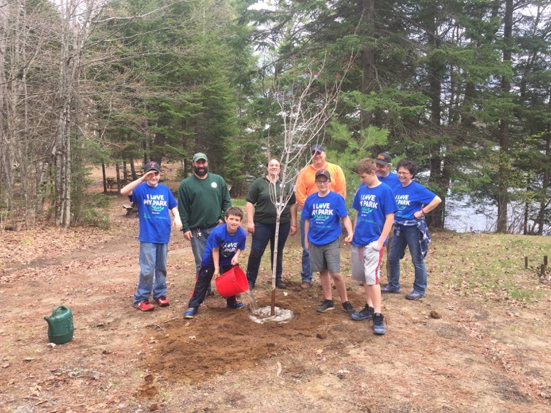 Volunteers at a campground help plant a tree