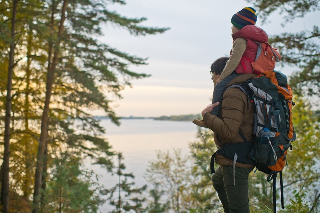 An adult hiker with a child on their shoulders