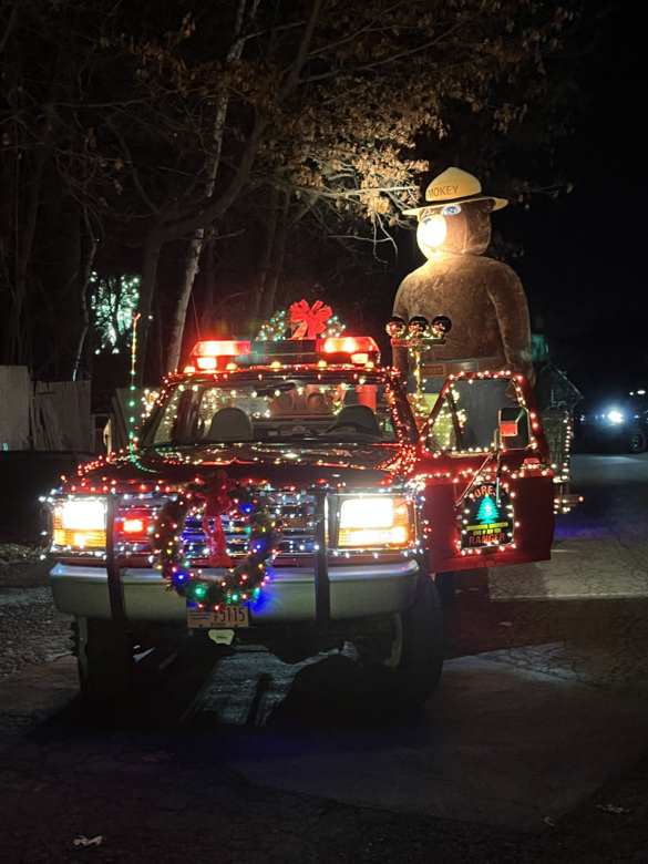 Forest ranger truck decorated in Christmas Lights with big Smokey Bear figurine in back at night