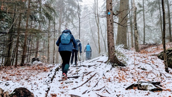 3 people hiking in a row up Cat Mountain, snowy winter day