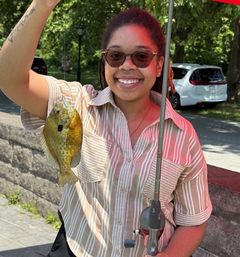 Person holding up a sunfish and a fishing rod