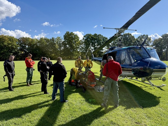 Rangers stand next to helicopter in a field