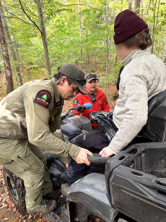 Ranger assisting injured hiker onto offroad vehicle