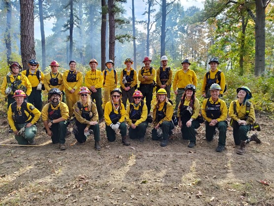 Group of Rangers in yellow take a group photo at wooded area