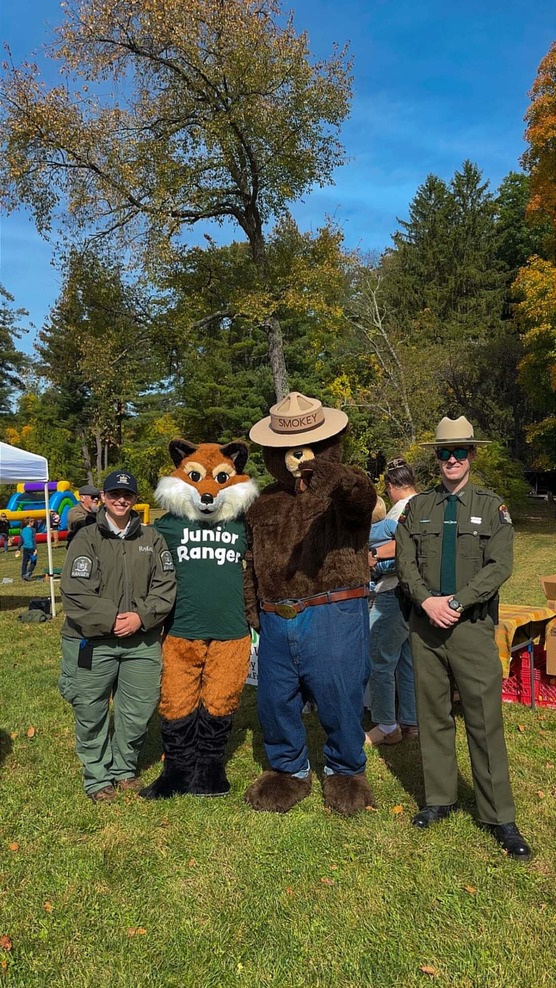 Smokey Bear mascott with two Rangers in a field