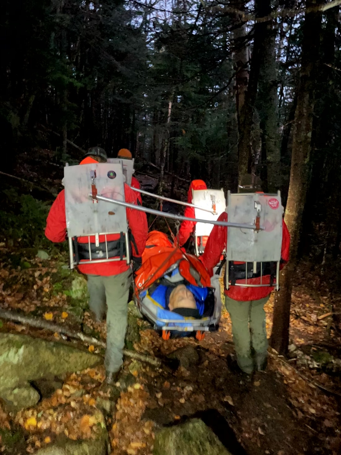 Rangers carry injured hiker down wooded trail