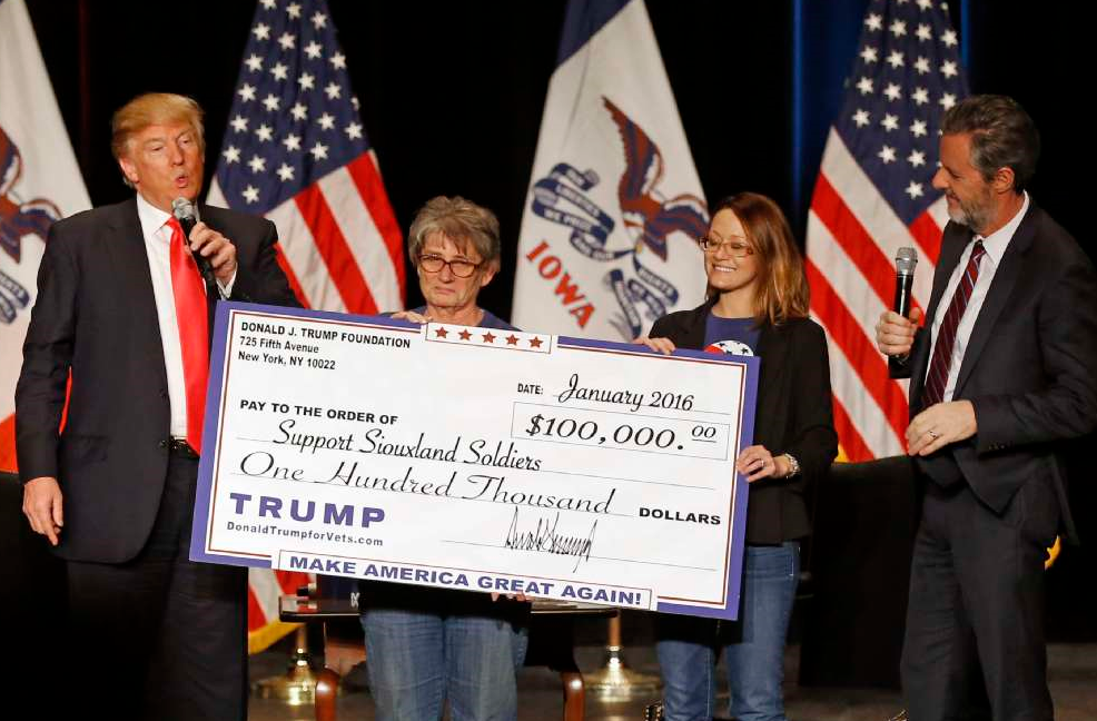 Donald J. Trump presents a one hundred thousand dollar check from the Donald J. Trump Foundation to members of the non-profit group, Support Siouxland Soldiers, days before the February 1st, 2016 Iowa caucuses.
