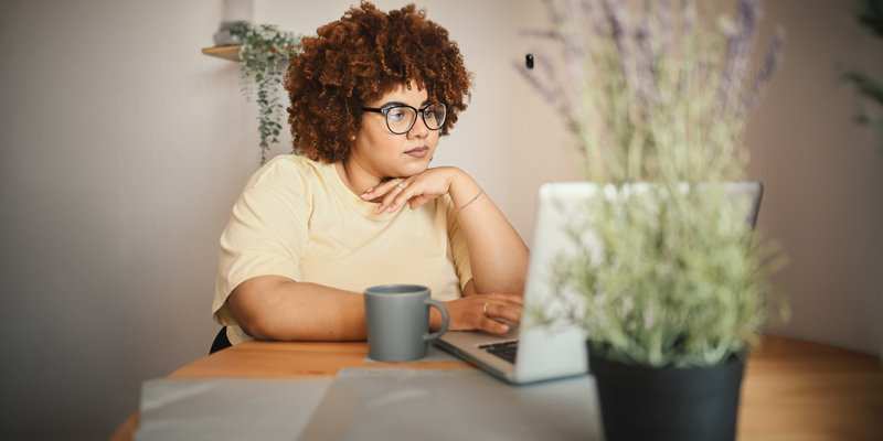 Person intently looking at laptop in a sunlit room