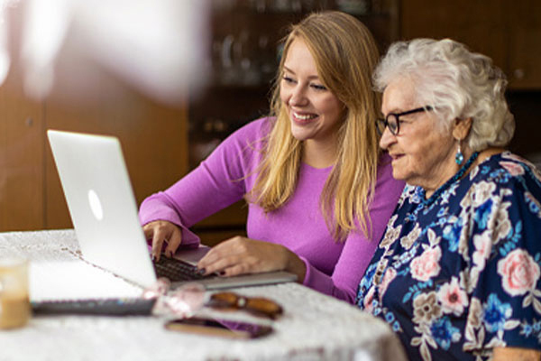 Mother and daughter sitting at table looking at laptop