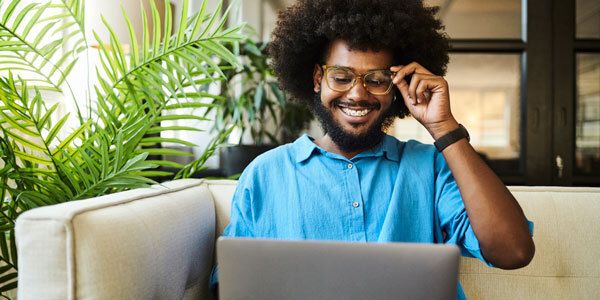 Gentlemen pushing up his glasses looking smitten while smiling at laptop 