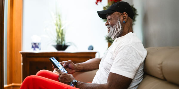 Gentleman sitting on couch and using his phone to check his New York State tax refund status