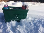 A recycling bin on a snow pile