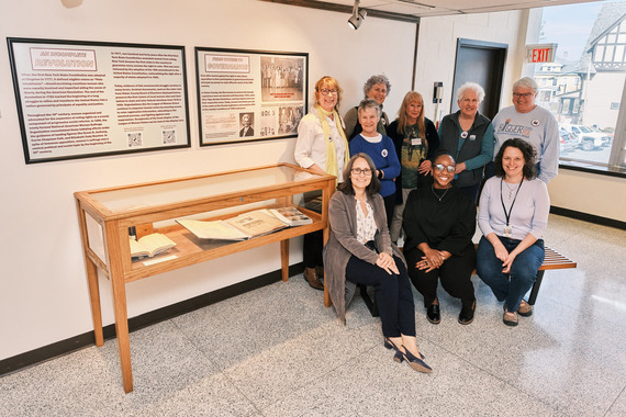Local female officials and community leaders next to a case of archival materials at the archive opening