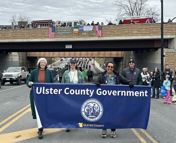 Chief Diversity Officer Dina Suggs and County Legislators marching in the St Patty's Day parade holding a banner that says Ulster County Government
