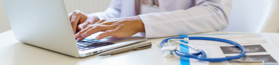 A medical professional typing on a laptop.