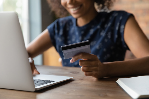 Person with credit card in hand and on laptop