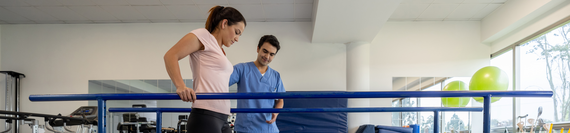 A physical therapist helping a person practice walking.