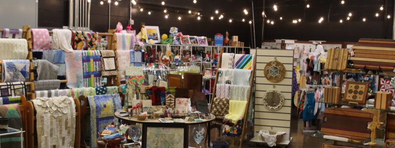 Holiday gift shop with various items including quilts and artwork 