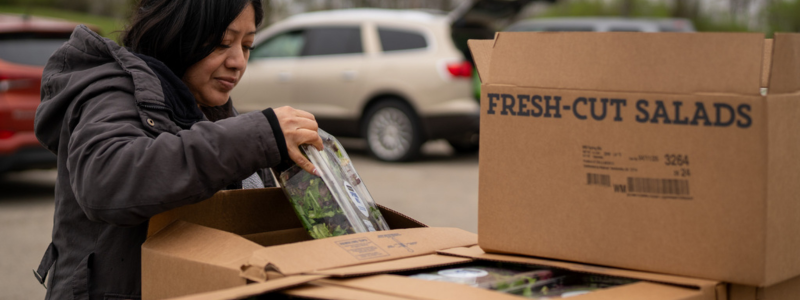 Lady selecting produce from box that says salad