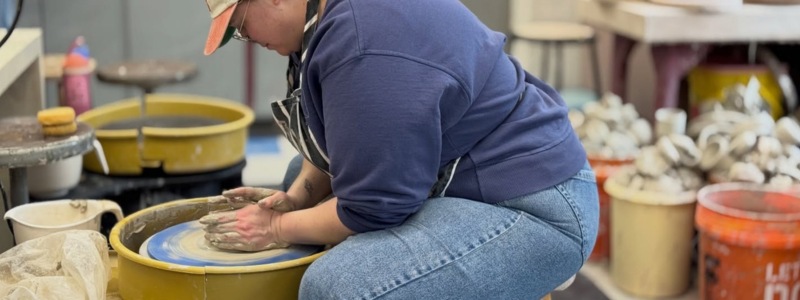 Person spinning clay on pottery wheel 