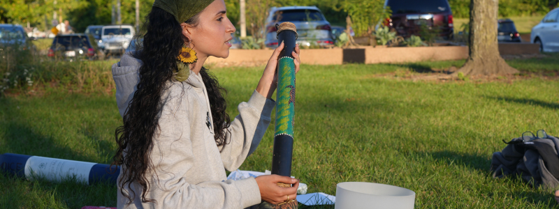 Woman sitting in grass holding sound device