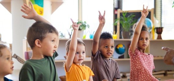 school kids raising their hands to answer a question