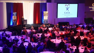 Director Wente speaking to a large crowd sitting at large round tables at CASA's Celebrate Kids Conference.