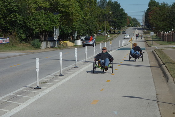 Two people using recumbent bicycles on a two-lane separated bike lane.