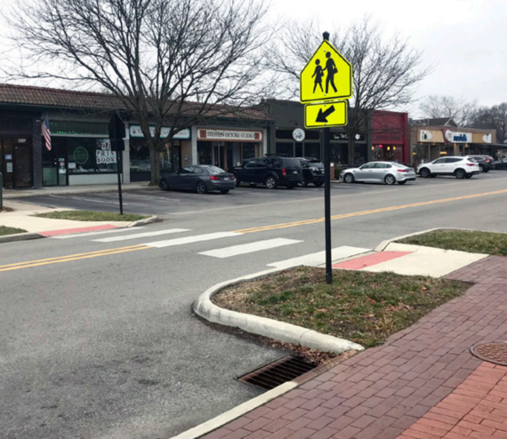 Curb extension at crossing with a pedestrian crossing sign in a shopping center. 
