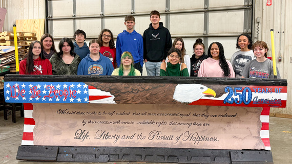 Photo of students posing with painted plow