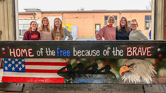 Hardin Northern art students standing behind a painted plow