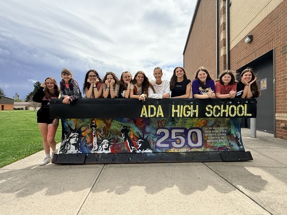 Ada High School art students stand behind a plow painted with Statue of Liberty