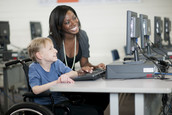Teacher assists a student with disabilities on the computer.