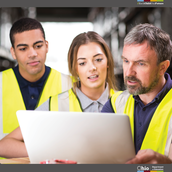 Two high school students working with an adult in an industrial setting.  All are wearing safety vests. 