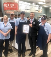 The crew from Jersey Mike's stands with Auditor Stinziano in front of the counter as they are presented with the True Transaction Award. 