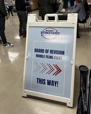 A advertisement for a Board of Revision Mobile Filing event inside a school gymnasium. 
