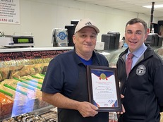 Auditor Stinziano poses with the owner of Carniceria Brother butcher shop in front of a deli case inside the store. 