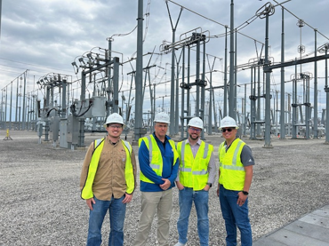 Rep. Holmes and three men with safety vests on near electrical equipment