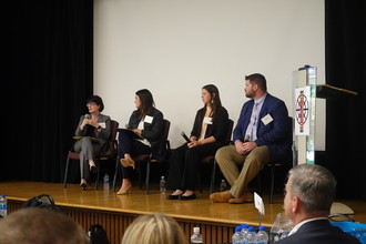 Director French and staff speaking on panel at conference