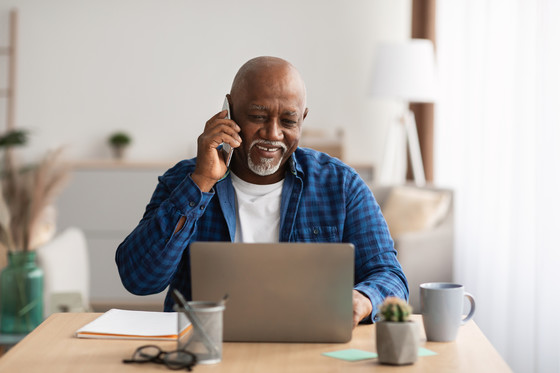 picture of man on laptop and talking on phone, smiling