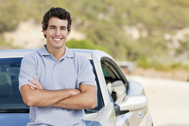 young mans standing in front of his car