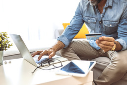Picture of man holding credit card typing on laptop