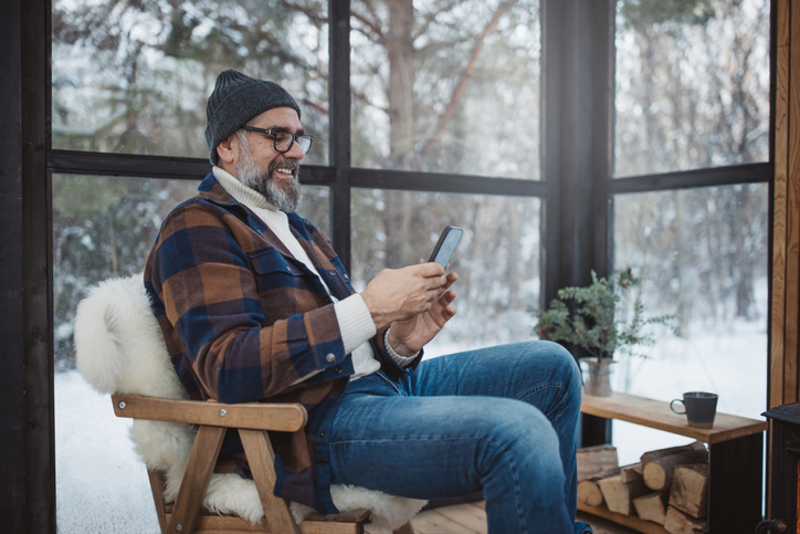 man in chair on phone winter outside window