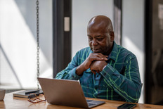 older man watching webinar on laptop 
