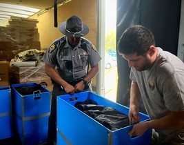 A State Highway Patrol officer help carry the protective gear going to Ukraine into a truck.